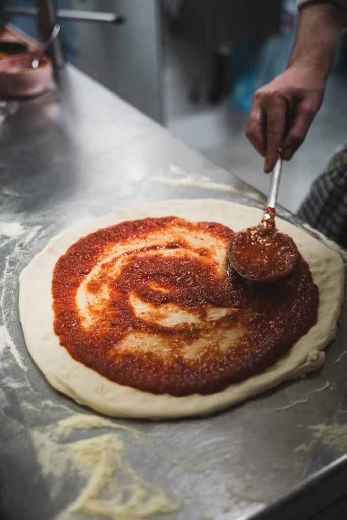 Pizza die wordt voorbereid met tomatensaus